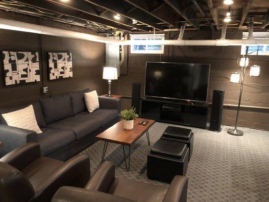 68 Townsend Street basement. 65" LG smart tv with Yamaha AV receiver, and Andrew Jones speakers.  Large seating area with  sofa, arm chairs