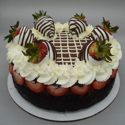 Rich Chocolate Cheesecake with white chocolate covered strawberries & whipped cream.