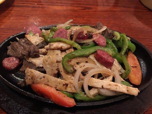 Parillada is a mixed grill or chicken and beef fajitas, smoked sausage, cilantro, bell peppers, tomatoes, and onions.