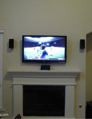 TV with speakers above mantle fire place