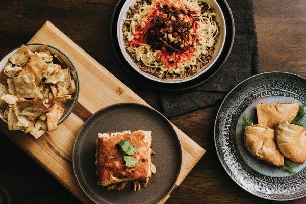 A selection of our favorite menu items! From left to right: za'atar chips, bechamel, koshary, and pita.