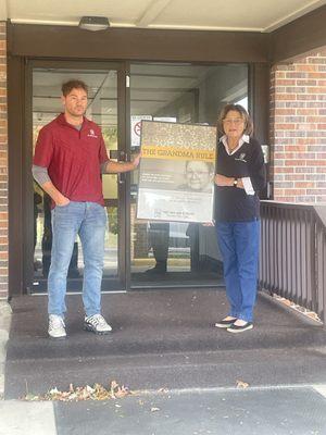 OWNERS CORY AND MARG CHRISTENSEN. HOLDING THE GRANDMA RULE SIGN.