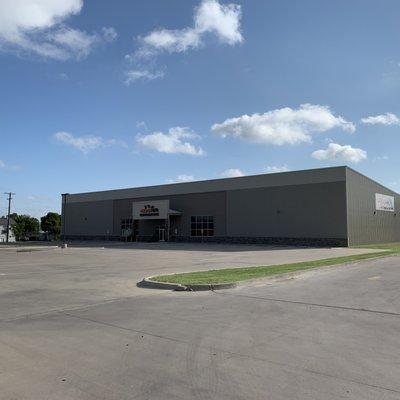 Close up of the front of Urban Air Trampoline Park from across the street to showcase view of parking lot and building.