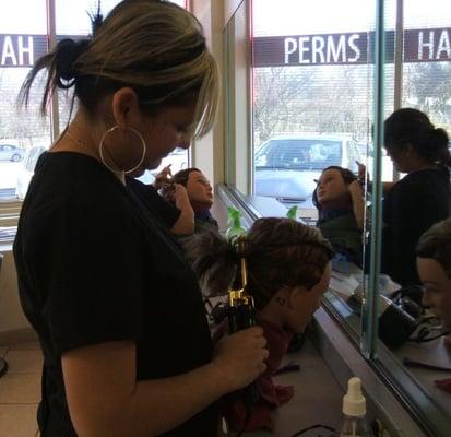 Beauty school students learning new hairstyles on their manikins.