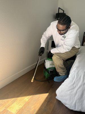 Pest control technician applying treatment around interior of other bedroom