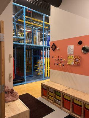 Play space entrance with cubbies for shoes and hooks for coats