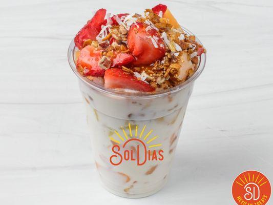 Fruit salad drenched in homemade sweet yogurt topped with shredded coconut  , granola, pecans and honey