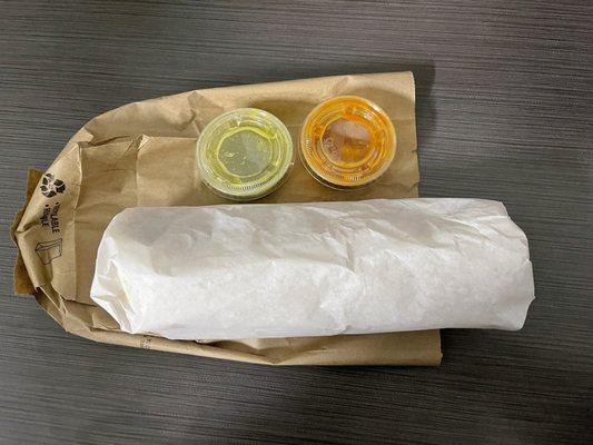 Huge wrapped up burrito with green and red salsa