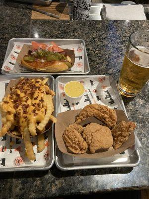 Chili cheese, fries, chicken tenders, and a Chicago hotdog with a Stella on the side