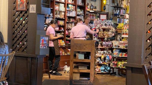 Hostess with the mostest on her phone again,  while two general store employees load up the stuffed animal carousel.