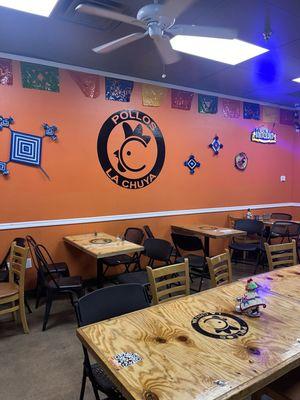 Interior distinctive wooden tables with a decorative wall with the logo of Pollos LaChuya