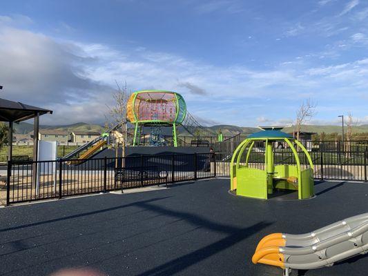 A rotating ride for children, with the older children, jungle gym in the background.