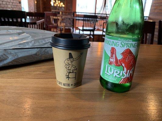 Small espresso cup and a bottle of sparkling water.