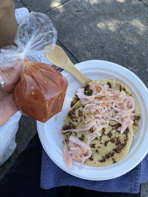 Vegan pupusa with slaw and hot sauce in a bag