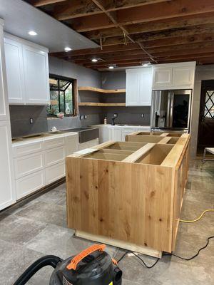 Rustic alder island with white wall cabinets a perfect blend of colors , materials and floating shelves to match island material