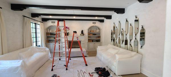 In the process of hanging a chandelier,  making sure all furnishings and floors are covered.