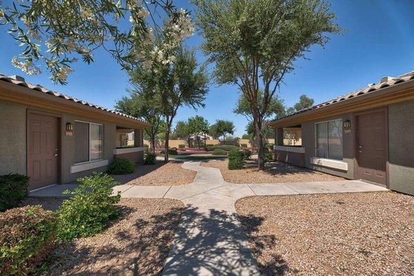 a courtyard between two buildings with trees and a pathway at Desert Sage