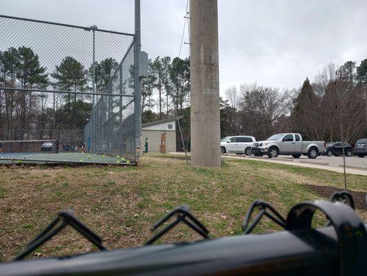 View of the edge of the tennis courts, the bathroom facilities, and the water bottle fill-up station