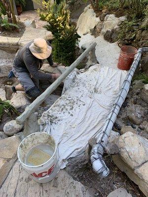 Installing a faux redwood concrete wooden bridge.