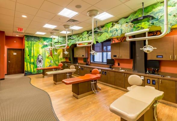 Open bay treatment area with fun safari theme and tv's above every chair!