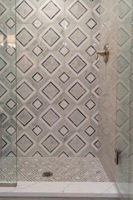 Decorative tile design work on the back shower wall.