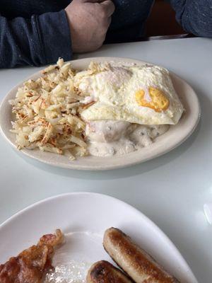 Husband's plate - 2 eggs over easy with biscuits and gravy with hash browns. Country Delight