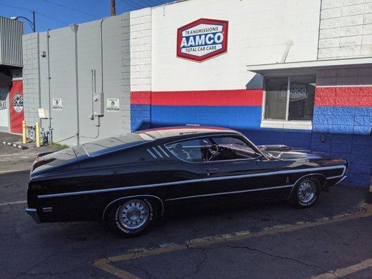 Rare vintage fastback Ford Cobra Jet flexing it's muscles under the AAMCO sign. 428 cubic inches of American horsepower.