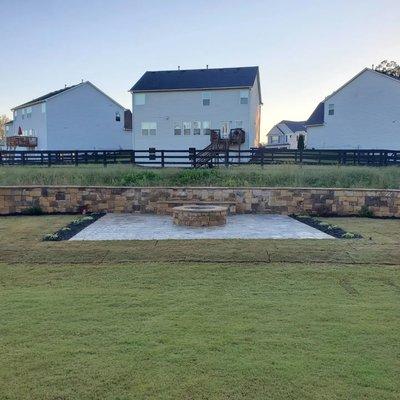 Natural stone fire pit and wall with sitting area, patio, sod, mulch and plants