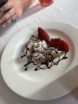 Cannolis with whipped cream, chocolate sauce and strawberries