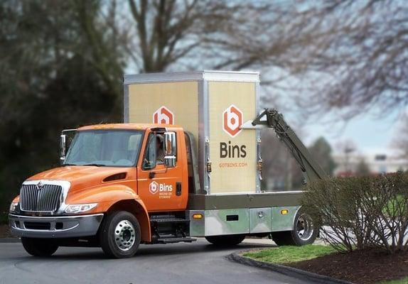 An earth-tone colored Bins container being delivered to a home.