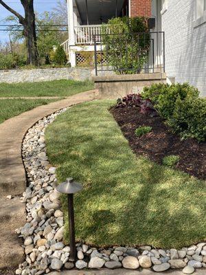 Redesigned front garden to improve drainage and maintenance. Reduced size of original garden, added river rock and sod, added plants.