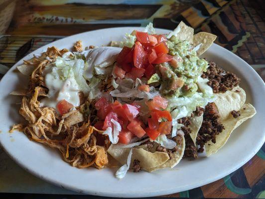 Super Nachos: Beans, beef, chicken, guacamole, sour cream, lettuce & tomatoes.