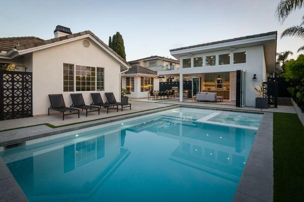 Breeze block wall for shower on the left. Modern pool with pool house & panoramic doors. Outdoor lighting