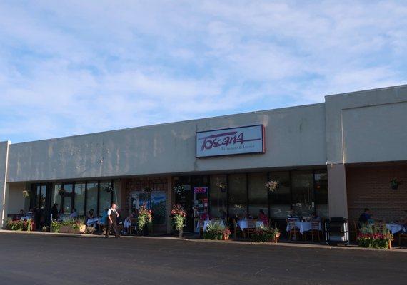 Strip mall storefront, with a lot of patio tables in use at the moment.