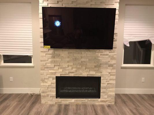 Gas fireplace with stone surround and mounted TV.