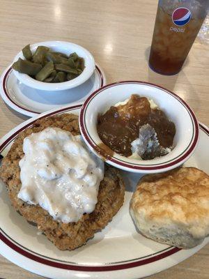 Country fried steak, mashed potatoes and green beans with a biscuit.