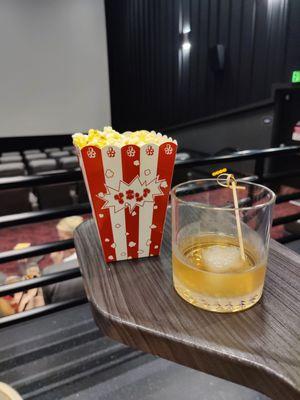 Smoked Bourbon (signature cocktail with smoke-infused ice) and the obligatory popcorn on the personal side table before the show starts!