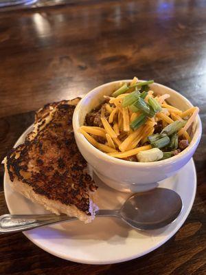 Cup of chili with a side of toasted jalapeño bread.