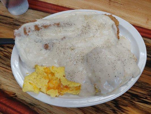 Chicken fried steak with scrambled eggs and biscuit and gravy.