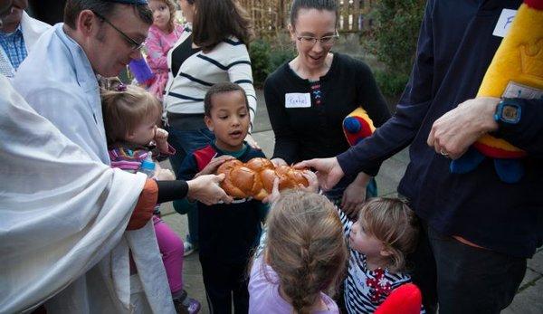 Tot Shabbat kids going in for a piece of challah.