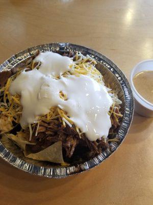 Shredded beef nachos with queso on the side.