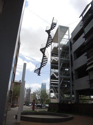 Spiral fire escape sculpture titled Architectural DNA between buildings