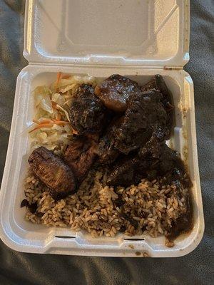 Brown stew chicken with rice and peas, cabbage, and plantains. Chicken falls right off the bone