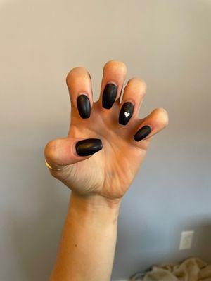 Almost 3 weeks of grow out and these talons still look amazing! Matte black dip powder nails, coffin shape, small white heart accent