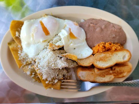 Green Chilaquiles with over easy eggs, beans, rice, and toast