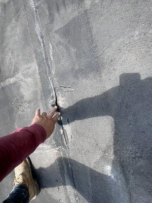 Examining a roof seam crack. Taurus Roofing & Siding offers expert repairs for all roofing issues.