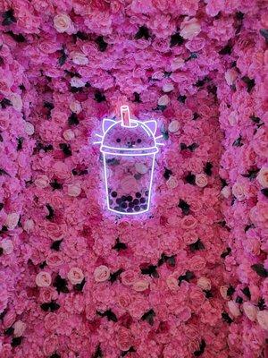 Cute flower wall with a boba cat neon sign.