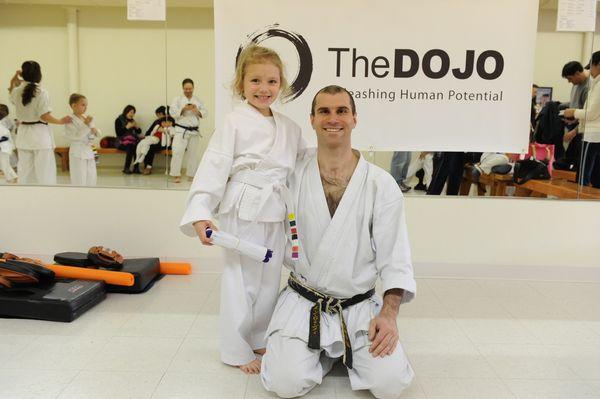 A new student earns their new belt, building one's self-esteem and confidence after the discipline focus of attending classes.