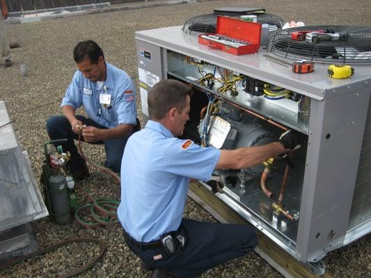 Technicians working on a commercial air conditioner.