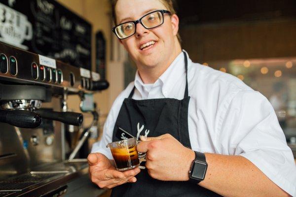 Sam proudly holding a freshly brewed shot of espresso.